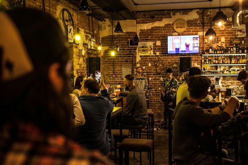 En full pub en kveld, med folk rundt bordene og et band som spiller ved baren