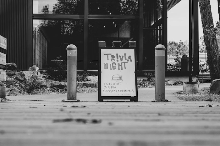 Et gateskilt med teksten «Trivia night, tonight 7–9 pm» foran et lokale